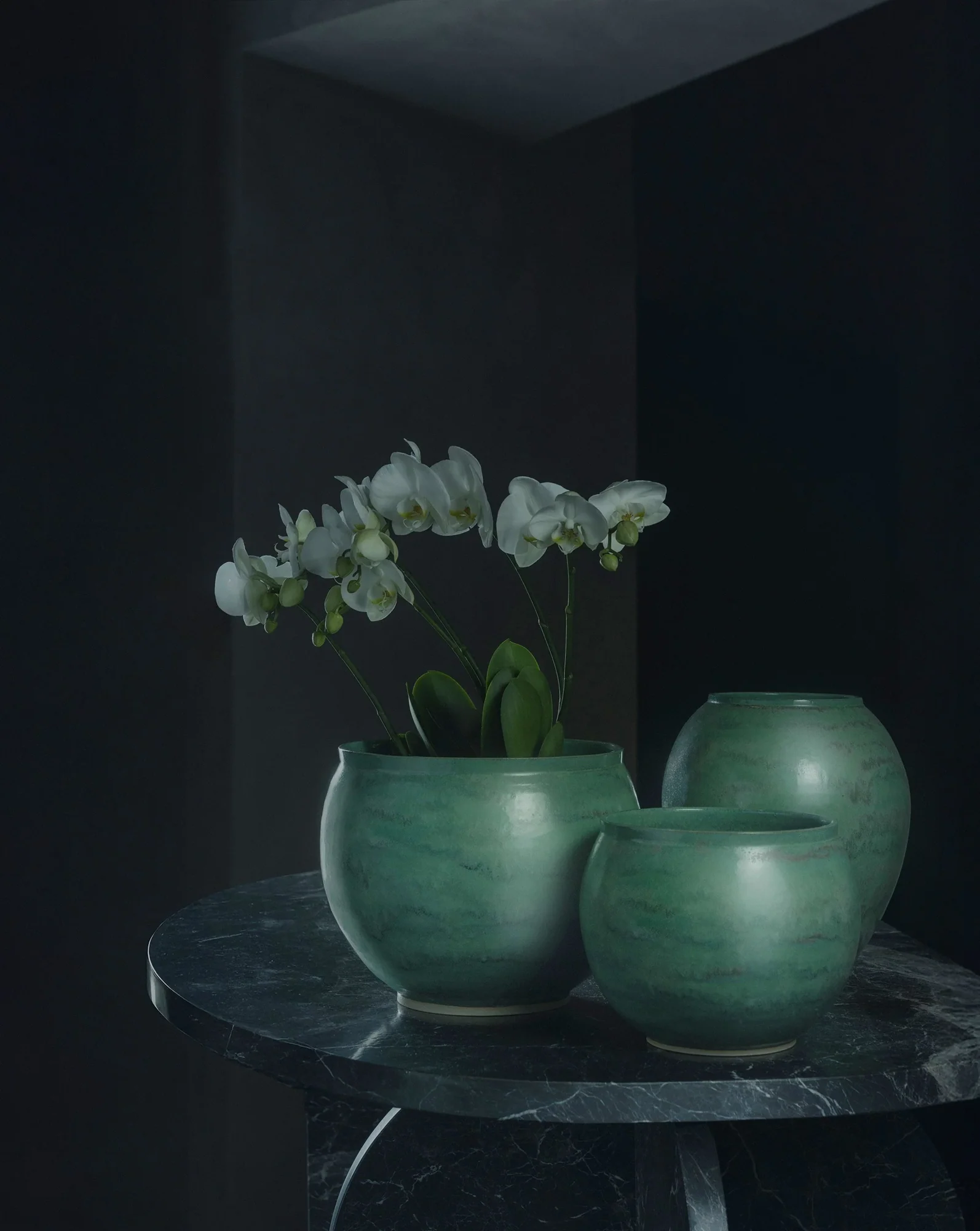 Jade-glazed ceramic pots, one planted with a white orchid, made for Kramer und Kramer